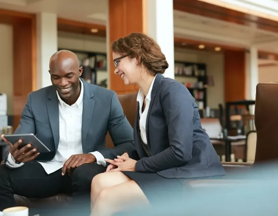 Executive level business people reviewing performance metrics on tablet during meeting